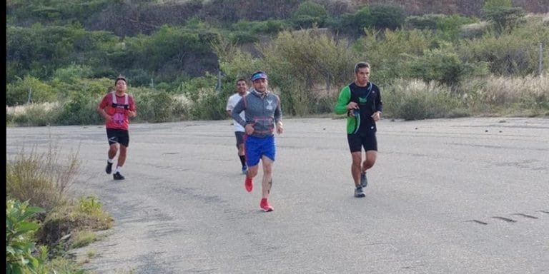 Corredores en una ruta de asfalto rodeada de vegetación durante una carrera al aire libre.